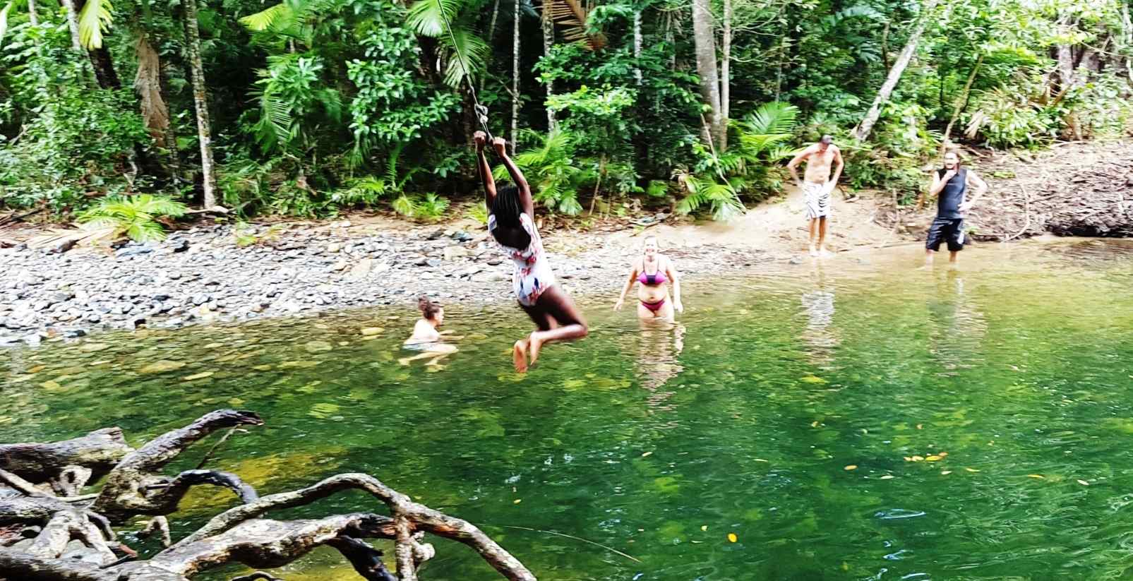 girl swinging on rope into water